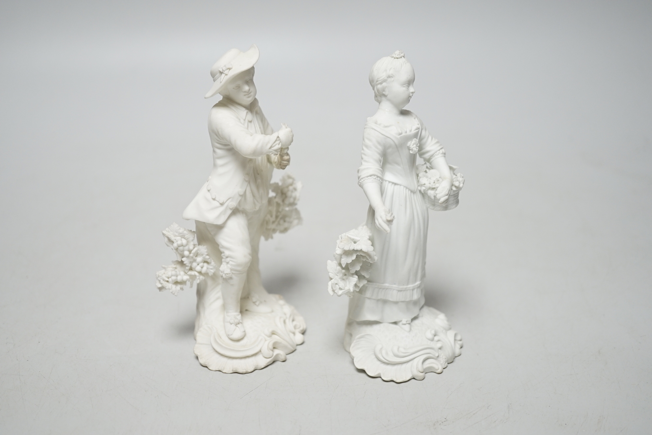 A pair of 18th century Derby biscuit figures of a man and woman, he with a bunch of grapes and she with a basket of flowers possibly representing Spring and Autumn, pattern number 125